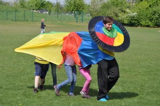 Betreuer und Kinder spielen auf der Wiese Try it (DE)