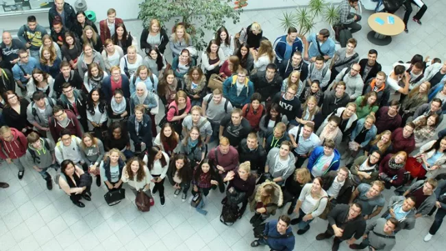 grosse_gruppe_studierende_wiwi_im_e-gebaeude_von_oben_2015_foto_y._weber_teasercut.jpg (DE)
