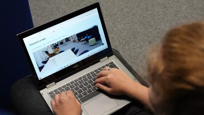 Studentin liest am Laptop in der Bibliothek