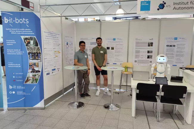 A2S Tag der Forschung 2023 stand setup with all posters, QTrobot, and a few presenters
