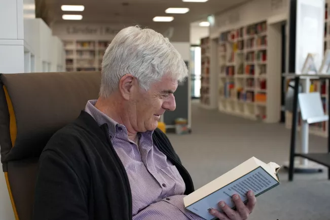 Dr. Armin Ehrhardt liest ein Buch in der Bibliothek